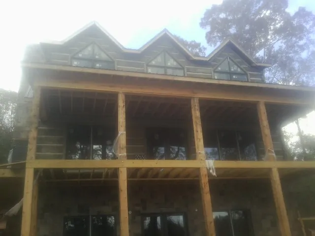 Dormers and porch framing on a large log home under construction — Roof Coating work by our crew in Saginaw